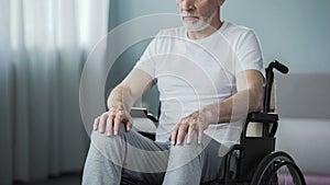 Helpless man with disabilities sitting in wheelchair and trying to move, health