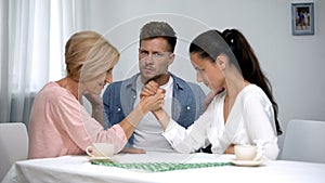 Helpless man looking at mother and wife arm wrestling competition, battle