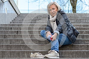 Helpless senior woman massaging her Foot