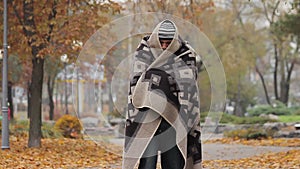 Helpless sick man feeling cold, wandering in city park covered with old blanket