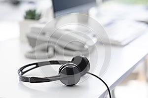 Helpline operator`s workplace with modern headphones at call centre, empty space