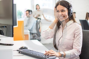 Helpline operator woman with headphones listening to a client in call centre.