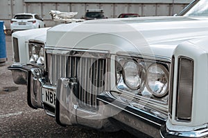 Classic american Cadillac car in store parking. Front detail of white luxury retro vintage automobile headlight