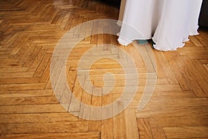 Hem of a wedding dress on a background of wooden floor with sparkles. Motion blur. Concept: wedding.