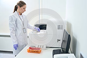 Hematologist laboratory assistant stands near an immunochemiluminescent analyzer