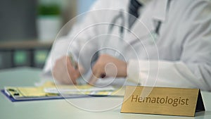 Hematologist prescribing treatment for hemophilia, filling out medical forms