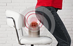 Hemorrhoid concept. Woman sitting down on chair with cactus near brick wall, closeup