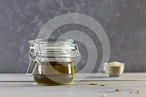 Hemp oil in a glass bottle, seeds and flour on a gray wooden background. Horizontal photo.