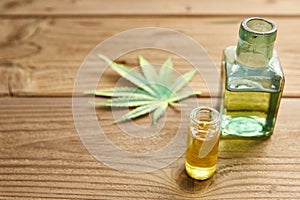 Hemp oil in a glass jar, hemp leaves on the background of wooden boards