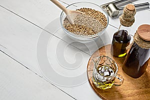 Hemp seed and garlic pressing masher on the table, oil in a glass jar and bottle on the background of wooden boards