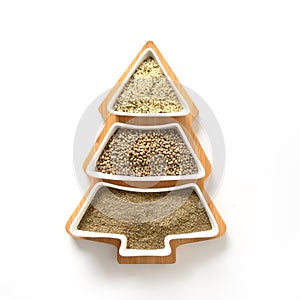 Hemp seeds, flour, kernels in plate shape of Christmas tree isolated on white. Alternative creative Xmas tree.