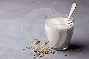 Hemp seeds in a wooden bowl and hemp milk on gray background