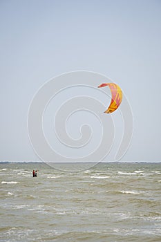 Henichesk, Ukraine - July 12, 2021: Kitesurfing. Practicing kitesurfing at summer beach. Kitesurfer doing tricks. People enjoy