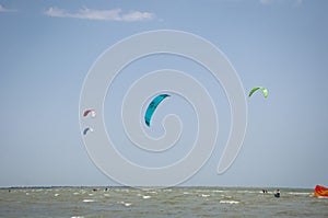 Henichesk, Ukraine - July 12, 2021: Kitesurfing. Seascape with kitesurfer in waves. Surfer in wetsuit doing trick in air against