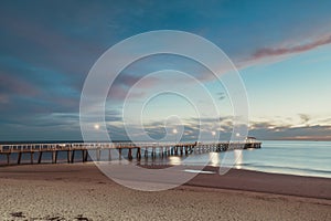 Henley Beach jetty at dusk with the tranquil sea embracing the weathered pillars