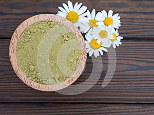 Henna powder in the coconut bowl and chamomile flowers