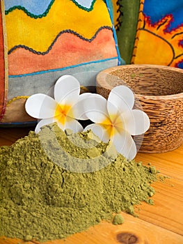 Henna powder in the coconut bowl and two tiare flowers