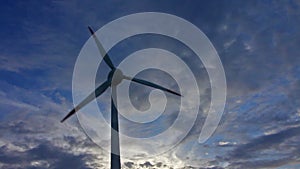 Heolic turbine rotating in the wind, sunset, sky with clouds