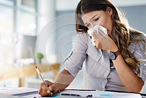 Her allergies are keeping her from being productive. a businesswoman working in her office while suffering from