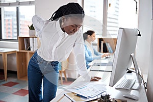 Her back is starting to act up. a young businesswoman experiencing back pain while working at her desk in a modern