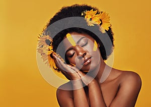 Her beauty is as delicate as a flower. Studio shot of a beautiful young woman posing topless with sunflowers in her hair