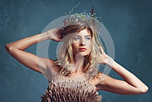 Her beauty reigns supreme. a young woman posing with flowers in her hair against a blue background.