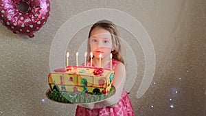 On her birthday, the girl blows out the candles on the birthday cake.