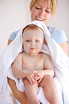 Her boy is clean and happy. a mother holding her baby boy in a towel.