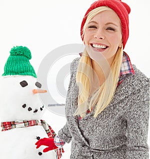 Her boyfriend was regretting not wearing his coat. a beautiful young woman standing beside a snowman.