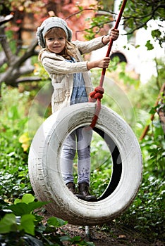 Her favourite part of the garden. Portrait of a cute little girl playing on a tire swing in the garden.