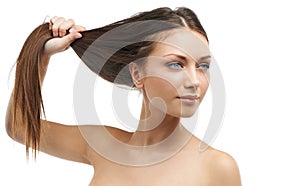 Her haircare product is working miracles. A beautiful young woman tugging at her hair while isolated on a white