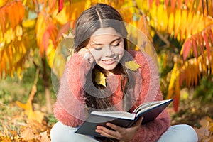 Her hobby is reading. Cute small child reading book on autumn day. Adorable little girl enjoy English literature