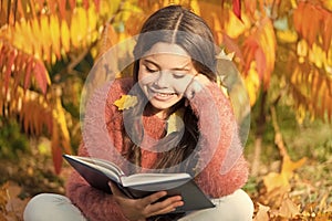 Her hobby is reading. Cute small child reading book on autumn day. Adorable little girl enjoy English literature