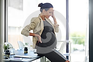 Her leave cant come fast enough. a pregnant businesswoman in discomfort in her office.