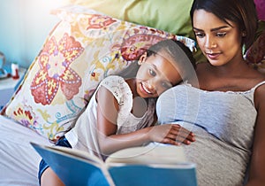 Her love for reading started with Mom. a mother reading a story to her little daughter at home.