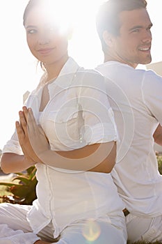 Her minds always on him. a young man and woman doing yoga outdoors.