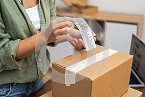 In her quest for an online shopping refund, a woman applies a barcode to a cardboard box for return