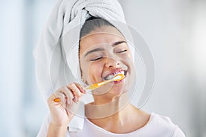 Her daily routine starts with fresh breath. a beautiful young woman brushing her teeth in the bathroom at home.