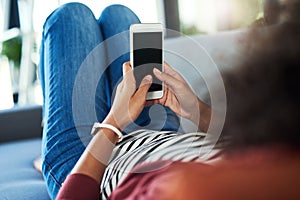 Her smart sofa day companion. a young woman using a mobile phone while relaxing on the sofa at home.