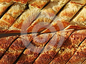 herb baguette with garlic butter and aromatic herbs in sunlight, top view macro food photography of bread