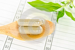 Herb capsule with green herbal leaf.