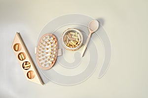 Herb in capsules in wooden bowl on pastel beige background. Beauty products for face and body skin care