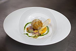 Herb croquette of goat cheese with ragu of roasted peppers along with roasted pistachios