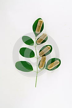 Herb moringa medicine capsules with  moringa leaves over on  white background.JPG