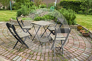 Herb spiral in the garden and table with chairs