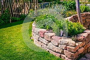 Herb spiral made of bricks for a small garden with green lawn