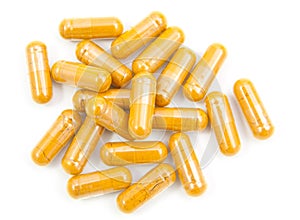 herb turmeric capsules spilling out of a bottle isolated on whi