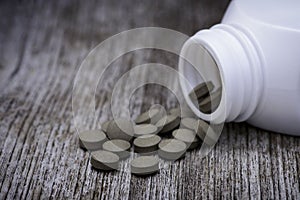 Herbal capsule medicine pill on wood table.