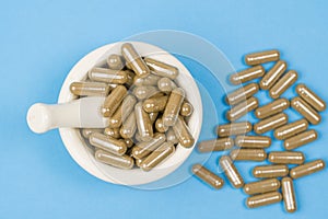 Herbal capsule and mortar on bluee background