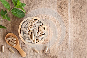 Herbal capsules in cup on wooden table background . Top view of medicine for healthy and capsules the spoon wooden